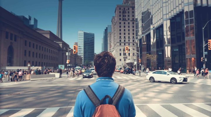 How to Start a Small Business in Ontario - A young man looking at Toronto CN Tower With Buildings